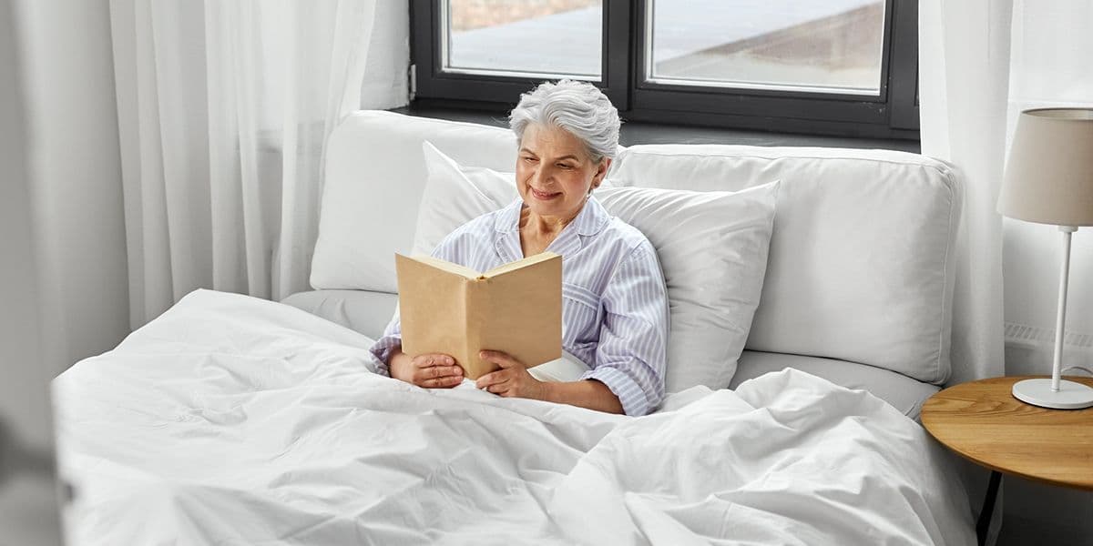 senior woman in the bed reading a book 